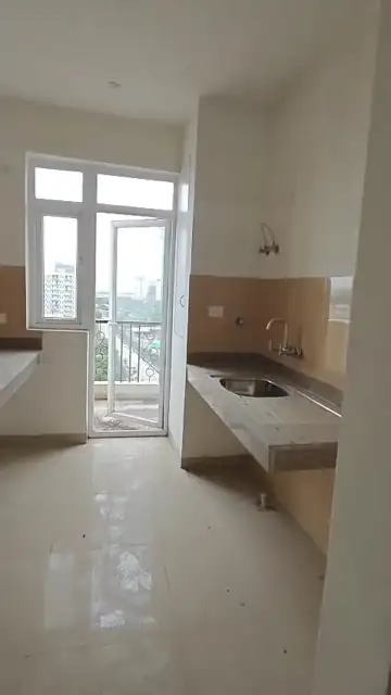 Kitchen with utility balcony access in the unused 3 BHK + 1 apartment for sale at Emaar Emerald Estate Sector 65 Gurgaon